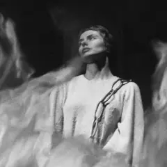 Ingrid Bergman, en ikonisk skådespelerska, bär en kedja över sin tröja, omgiven av drömska, dimmiga former.