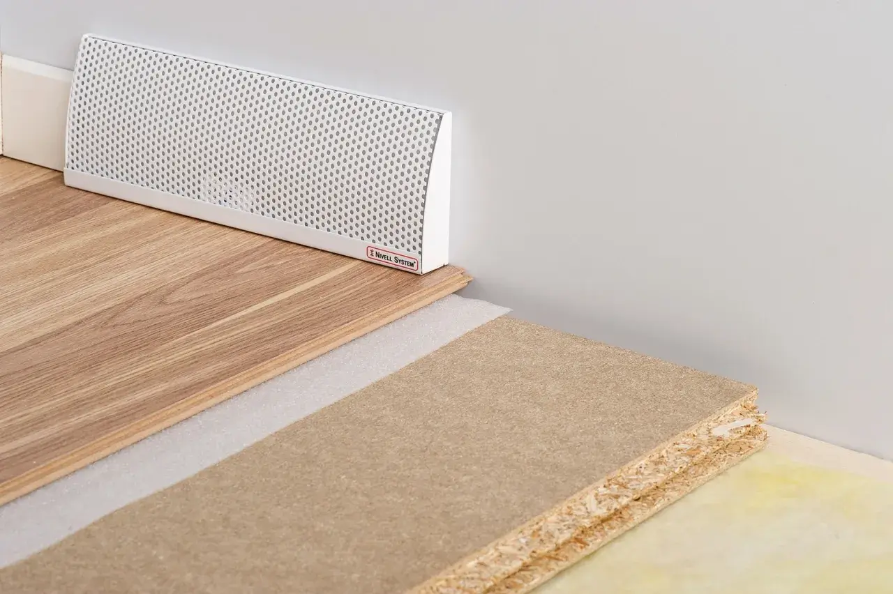 En vit ventilationsgaller för ett passivt ventilerat golv, med trägolv och byggmaterial.